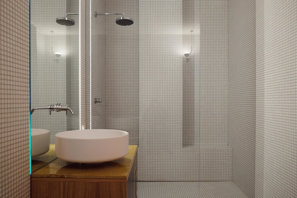 allenarchitettura - La doccia, completamente trasparente e divisa dal resto del bagno da una lastra di vetro tagliata di netto, conclude la scena in fondo. Abbiamo creato due nicchie nel muro, una per gli asciugamani e una per farsi una doccia in completo relax anche da seduti, inclinando a piacimento il soffione.