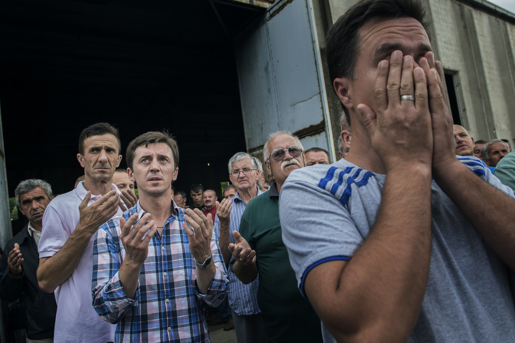 Photographer Anna Tärnhuvud - Admir Buljubasic prays when the truck with his father and the others remains come to Srebrenica.