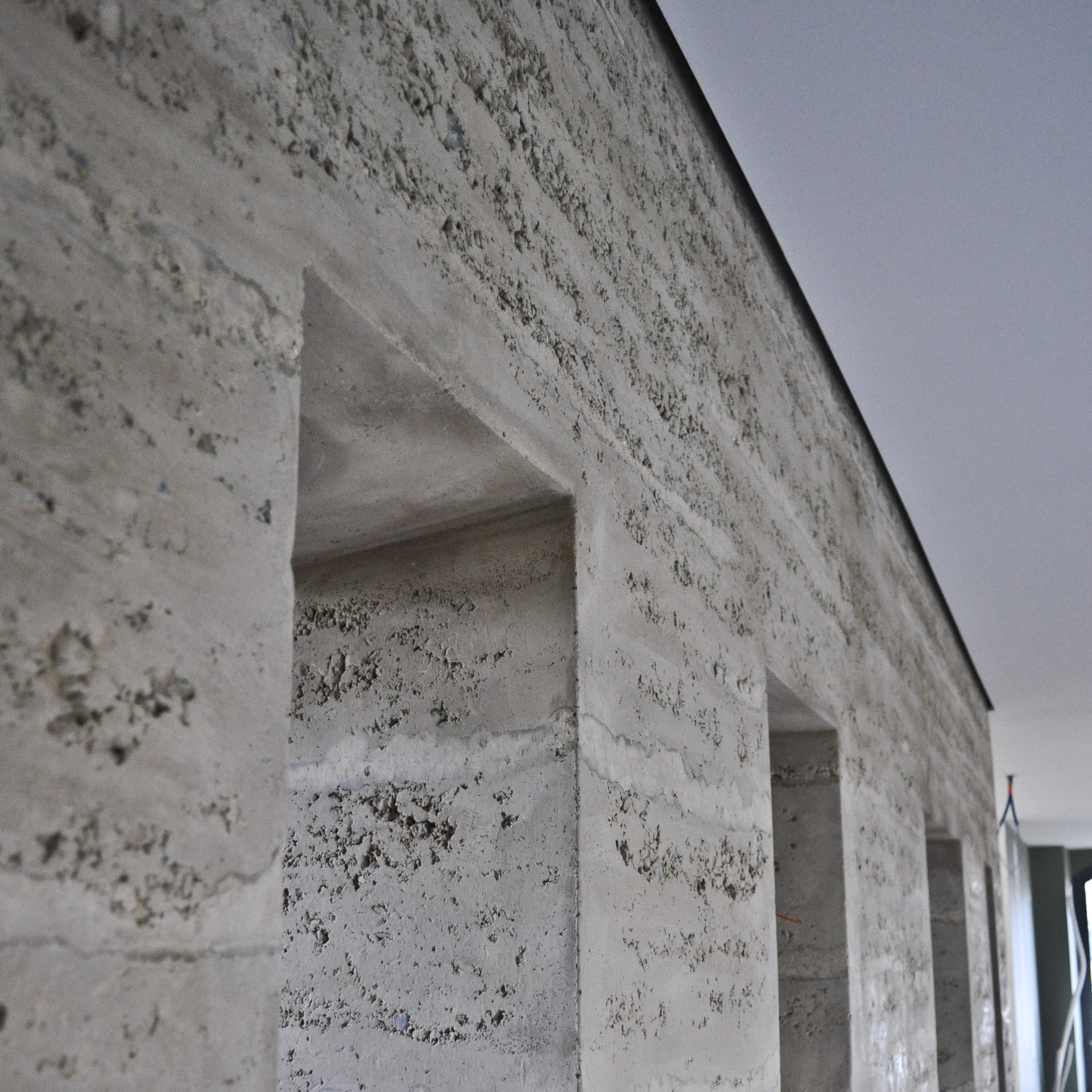 Un mur en pisé intérieur avec des ouvertures en biais et des spots — free download