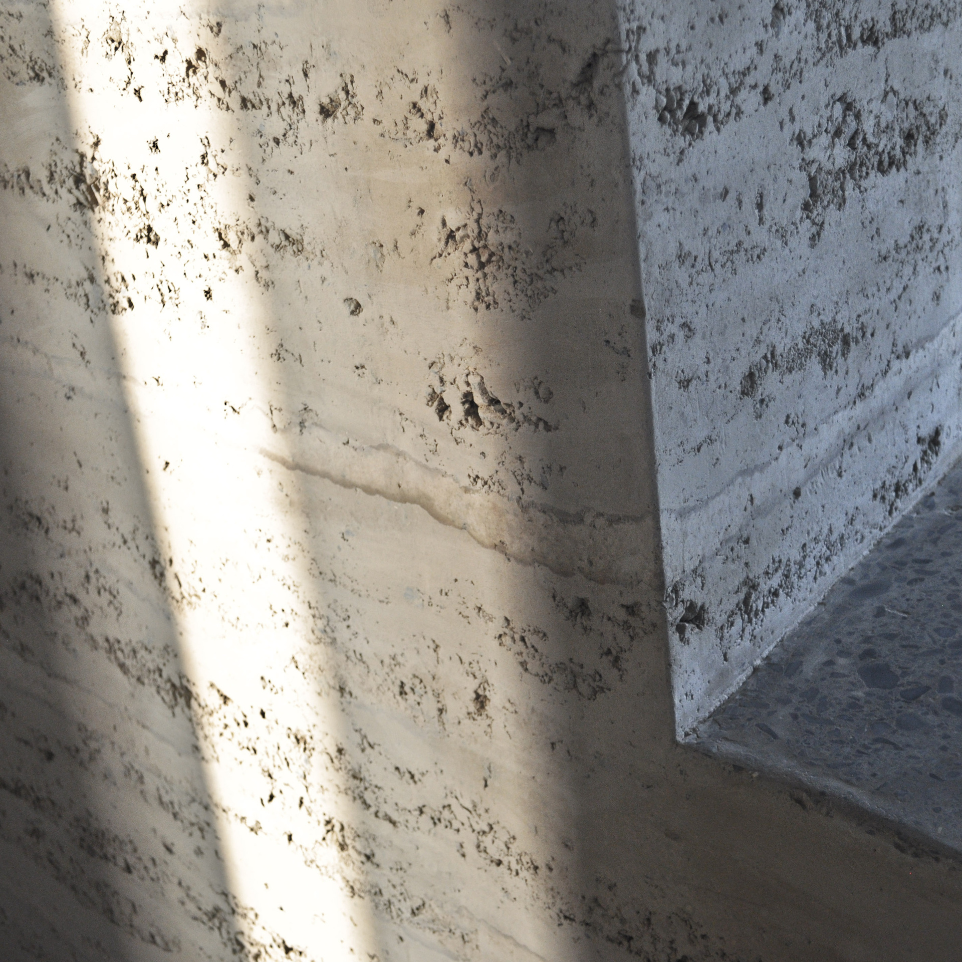 Un mur en pisé intérieur avec des ouvertures en biais et des spots — free download